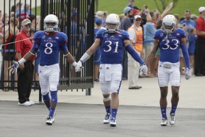 Kansas players Nick Harwell (8), Ben Heeney (31) and Cassius Sendish (33) walk onto the field before an NCAA college football game against Central Michigan Saturday, Sept. 20, 2014, in Lawrence, Kan. (AP Photo/Charlie Riedel)